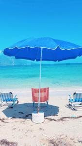 奥里库姆Bonbon Sea Apartment的海滩上的两把椅子和一把遮阳伞