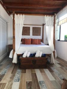 安提瓜La Aurora的一间卧室设有一张天蓬床和木地板。