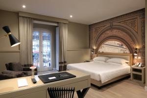 那不勒斯卡鲁索广场精品和健康套房酒店的酒店客房配有一张床、一张书桌