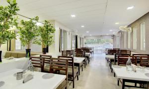 奥兰加巴德Treebo Trend Lalaji's Executive的餐厅设有白色的桌子和木椅