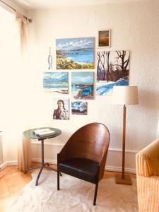 拉绍德封Appartement 1Bijou的一间设有桌子和椅子的客房,墙上挂有图片