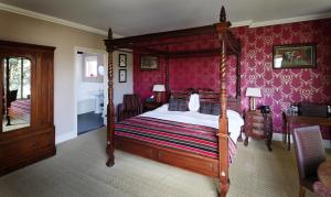 Farnham博物馆旅馆的一间卧室配有天蓬床和粉红色壁纸