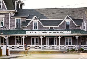 新肖雷汉姆Block Island Beach House的一个人在岛边的别墅前骑着自行车