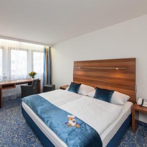 科尔恩塔尔-明欣根诺夫斯特罗告酒店的酒店客房设有一张大床和一张书桌。