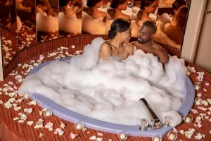 波科诺山天堂小溪度假酒店的男人和女人坐在浴缸里,浴缸里充满泡沫