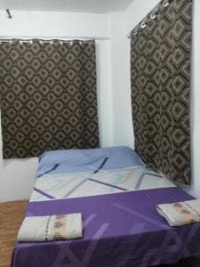 马尼拉马卡蒂经济一室公寓的一张带紫色棉被和床头板的床