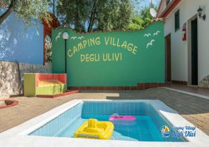 马蒂纳塔Camping Village degli Ulivi的建筑前的游泳池,有标志
