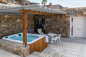 超级天堂海滩Etesians Suites & Villas的一个带石头墙的庭院内的热水浴缸