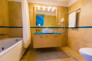 卡马利ansa豪华套房酒店的一间带水槽、浴缸和卫生间的浴室