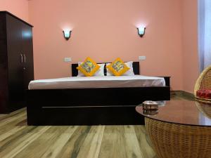 拉瓦格拉Kitsel Homestay的一间卧室配有一张带黄色枕头和桌子的床