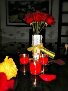 Valle de San JoséHotel el Paraíso del Valle的一张红蜡烛和玫瑰花瓶的桌子
