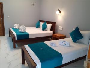 亭可马里MRD Beach Hotel的蓝色和白色的客房内的两张床