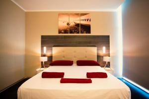 多索博诺维罗纳机场星级酒店的卧室配有一张带两个红色枕头的大型白色床