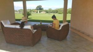 卡布拉斯Agriturismo Sa Ruda的两名妇女坐在庭院的藤椅上
