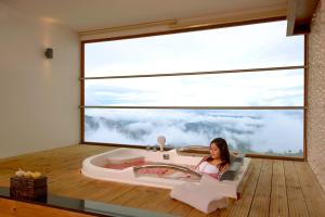 蒙纳Amber Dale Luxury Hotel & Spa, Munnar的坐在浴缸里的女士,位于一个设有大窗户的房间