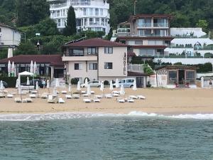 金沙Family Hotel Piter的海滩上设有椅子和遮阳伞,还有建筑