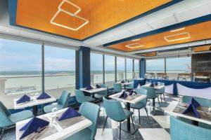 仰光Hotel Balmi的餐厅设有蓝色的椅子和桌子以及窗户。