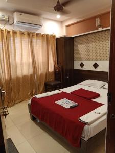 迈索尔hotel sangeeth lodging的一间卧室配有一张带红色毯子的床