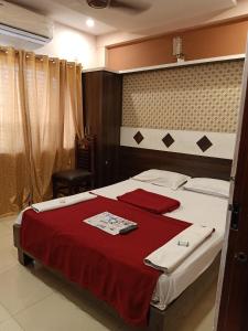 迈索尔hotel sangeeth lodging的一间卧室配有一张带红色毯子的大床