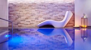 莱比锡奥恩瓦尔德旅馆的一座游泳池,旁边是砖墙,配有白色椅子