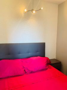格吕桑La Pinède的一间卧室配有一张红色的床和黑色床头板