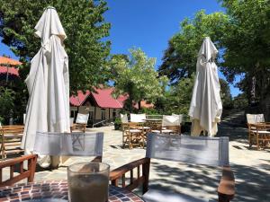 特罗多斯特鲁多斯居比利酒店的庭院里设有两张桌子、白色遮阳伞和椅子
