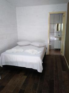 格拉玛多Chalé da Tranquilidade的卧室内的一张带白色床单和枕头的床