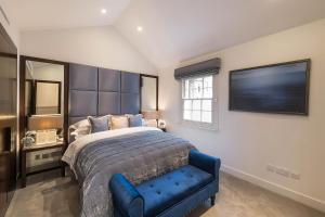 伦敦Spectacular Knightsbridge House Harrods 1 minute的一间卧室配有一张大床和一张蓝色椅子