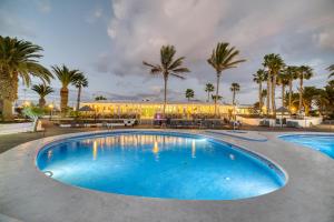 普拉亚布兰卡奥纳拉斯布里萨公寓式酒店的一座棕榈树大型游泳池和一座建筑