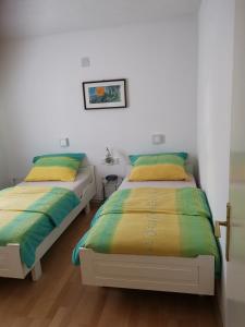普莱曼图拉Apartma Sonček的配有白色墙壁和木地板的客房内的两张床