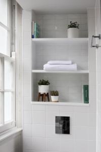伦敦Inhabit Southwick Street, a Member of Design Hotels的白色瓷砖浴室设有植物白架