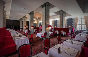 瓦朗西纳Royal Hainaut Spa & Resort Hotel的用餐室配有白色的桌子和红色的椅子
