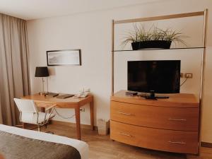 克雷塔罗水星酒店的酒店客房设有书桌和梳妆台上的电视