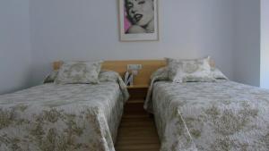 奥维多PENSION OVIEDO的一间卧室配有两张床和一张带照片的桌子