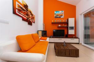 索利纳Seafront Apartment Soline With Seaview的橙色的客厅配有沙发和电视