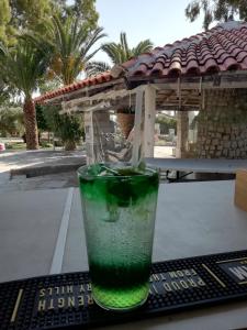 斯卡拉索提罗斯Marti Resort的坐在桌子上的玻璃杯里喝的一杯绿色饮料