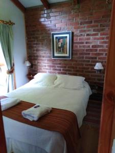 普孔Cabañas Spa Bungalows Huarranchi的砖墙房间的一个床位