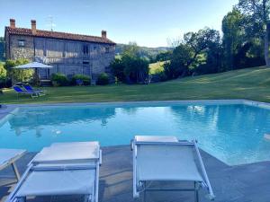 卡尔佩尼亚Country House "Locanda Le Querce"的游泳池旁的两把椅子