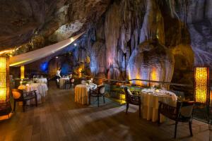 怡保万雅岚温泉度假村 的洞穴里的餐厅,配有桌椅
