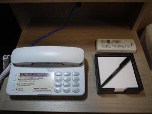 柏市Hotel Route-Inn Kashiwa Minami -KOKUDO 16GOU ZOI-的一张办公室电话和一张桌子上的计算器