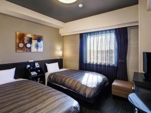 柏市Hotel Route-Inn Kashiwa Minami -KOKUDO 16GOU ZOI-的酒店客房设有两张床和电视。
