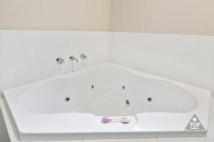 朱里恩湾朱里恩湾旅游公园酒店的浴室内设有带2个水龙头的白色浴缸