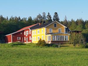 HarmångerNygården B&B Hälsingegård的田野上一座黄色和红色的大房子