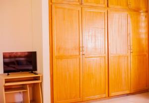 阿克拉Charis Home Services的客房设有木制橱柜和电视。