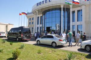 乌尔根奇Hotel Uzbekistan的一群人站在酒店外面,坐一辆公共汽车