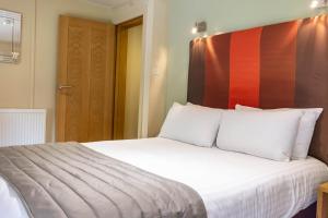 彼索普斯托福传统大哈林勃利庄园酒店的卧室配有白色床和红色床头板