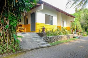 沙拉迪加RedDoorz near STAB Syailendra Kopeng的黄色和白色的房子,前面有楼梯