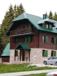 扎布利亚克Apartments Durmitor的一座带绿色屋顶的大型木制房屋