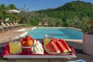 Ponticino博吉奥德尔L德拉戈乡舍住宿加早餐酒店的游泳池畔的桌子上放着一盘水果和果汁
