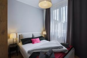 格但斯克Central Apartments Rajska的一间卧室配有一张带粉红色枕头的床